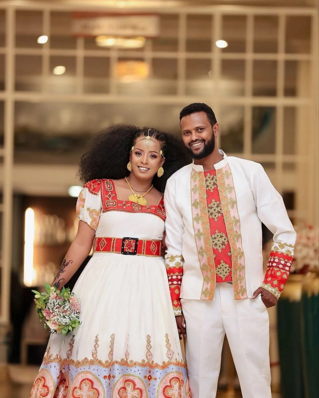 Elegant Habesha Couple's Attire with Vibrant Red and Gold Embroidery for Weddings